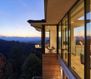 Villa moderne avec beaucoup de verre, donnant sur les montagnes californiennes à la tombée de la nuit.