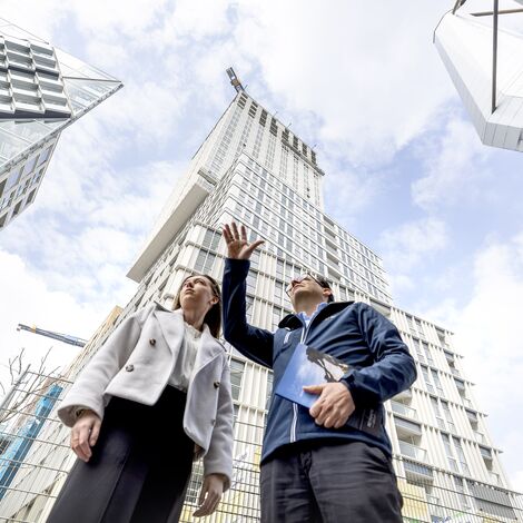Un homme et une femme pointant du doigt et parlant d’immeubles de grande hauteur.