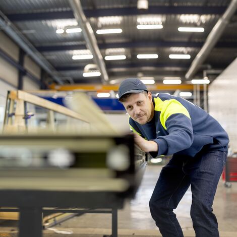 Fabbricante che allinea i profili delle finestre, indossando l'equipaggiamento di sicurezza.