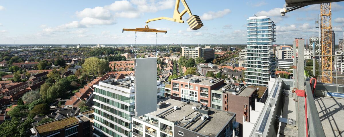 Panneau de construction modulaire soulevé à côté d’un gratte-ciel.