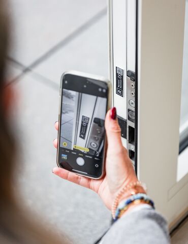Smartphone che tiene la mano vicino al codice QR sul profilo della finestra bianca.