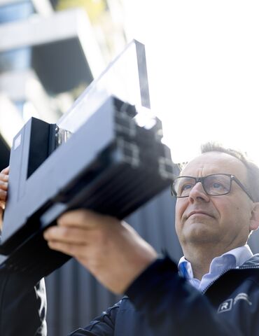 Mann mit Brille schaut sich Aluminium-Eckprobe genau an.