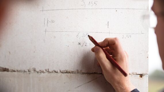 Homme écrivant au crayon sur le mur en béton du chantier de construction.
